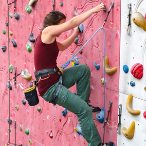 Une femme fesant de l'escalade à l'intérieur.